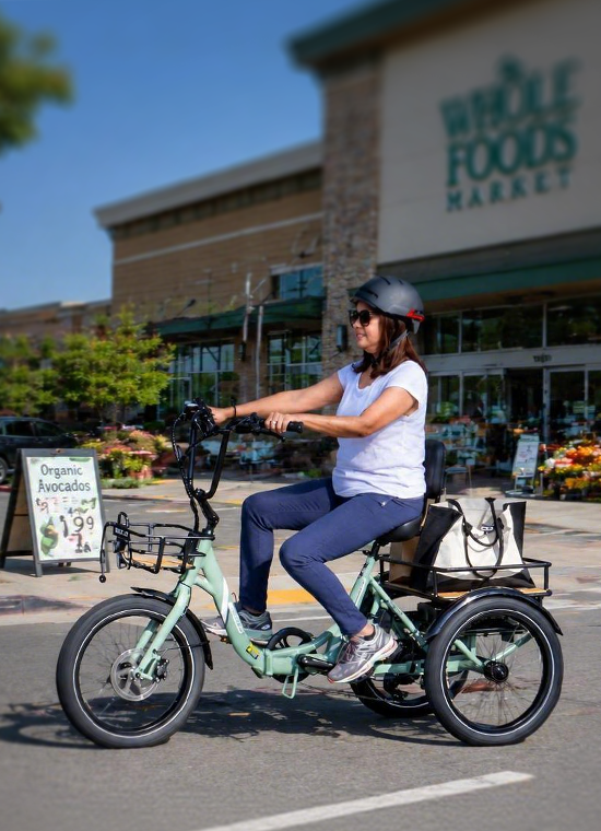 A rider lifting flowers into the rear basket of a standard EMOJO trike